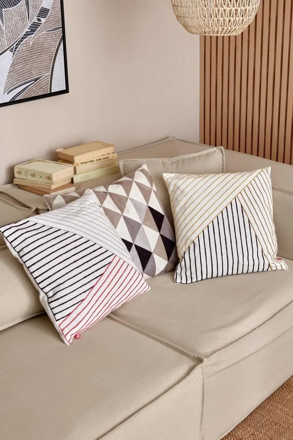 Beżowa sofa z dekoracyjnymi poduszkami w geometryczne wzory.